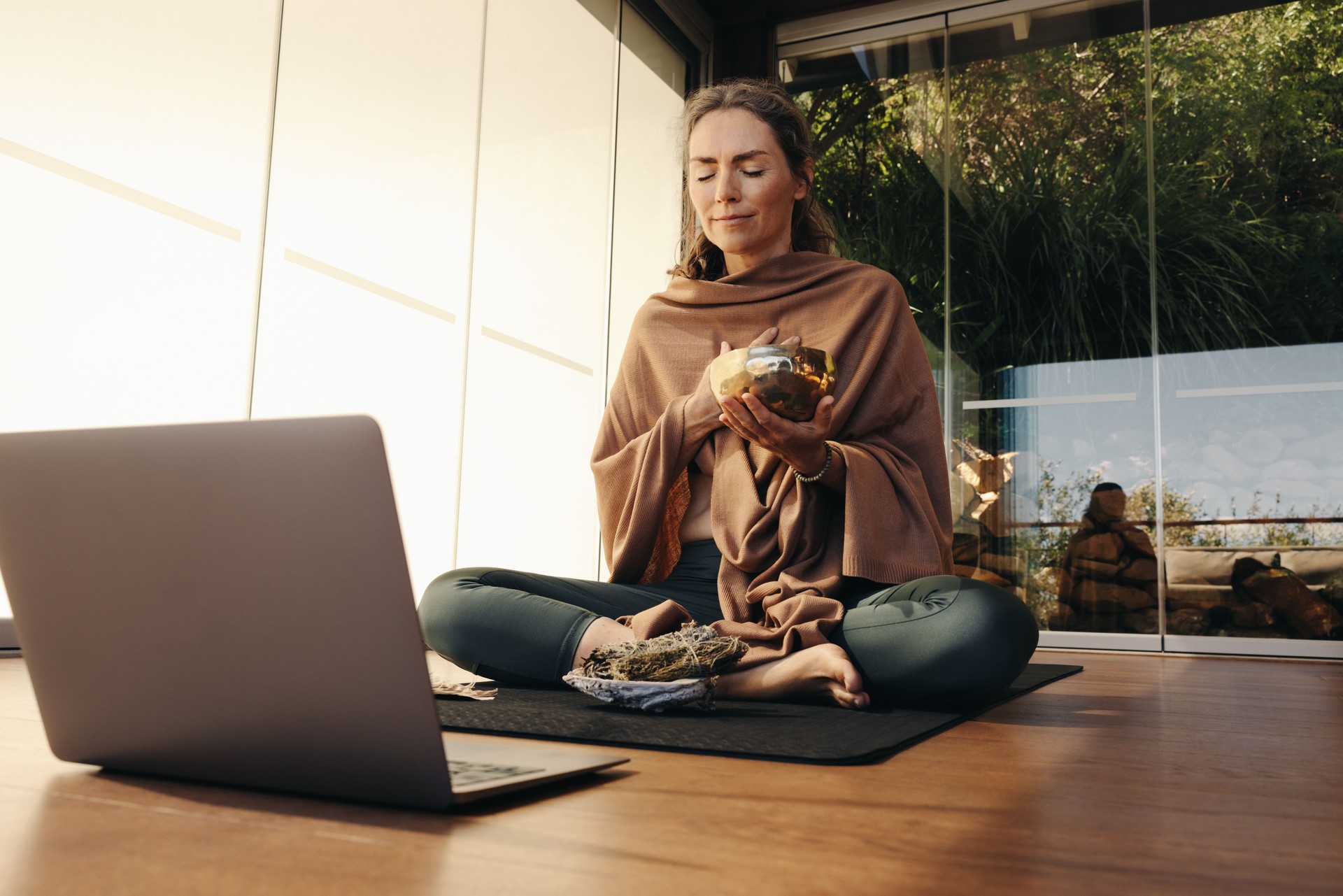 Ayurvedic healer meditating with a singing bowl and sage online